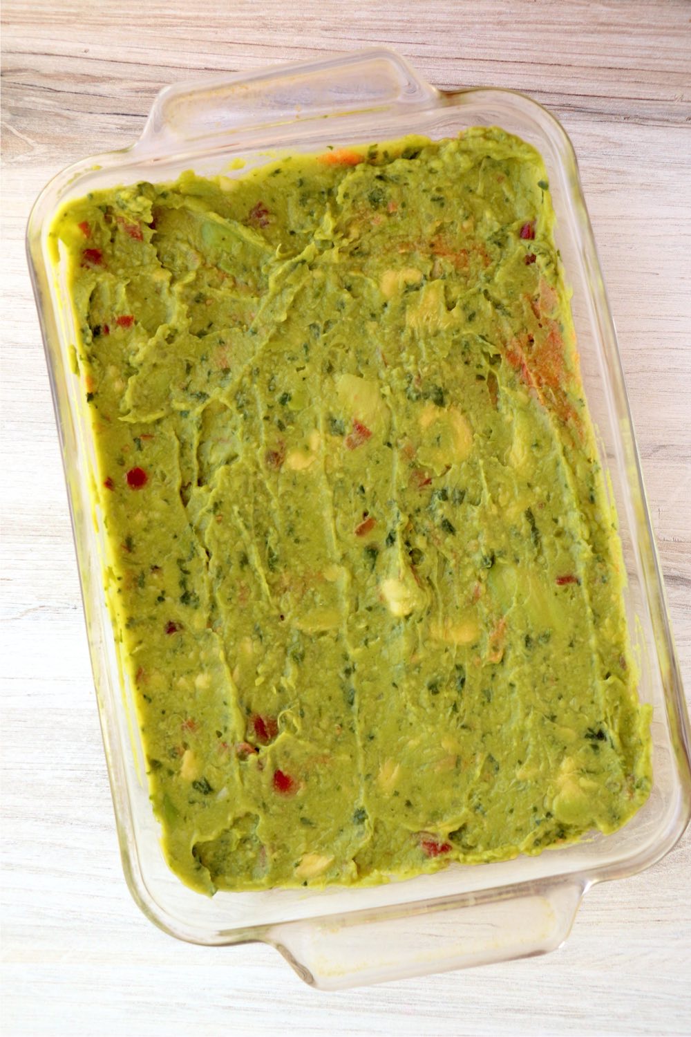 layer of guacamole spread out in glass pan