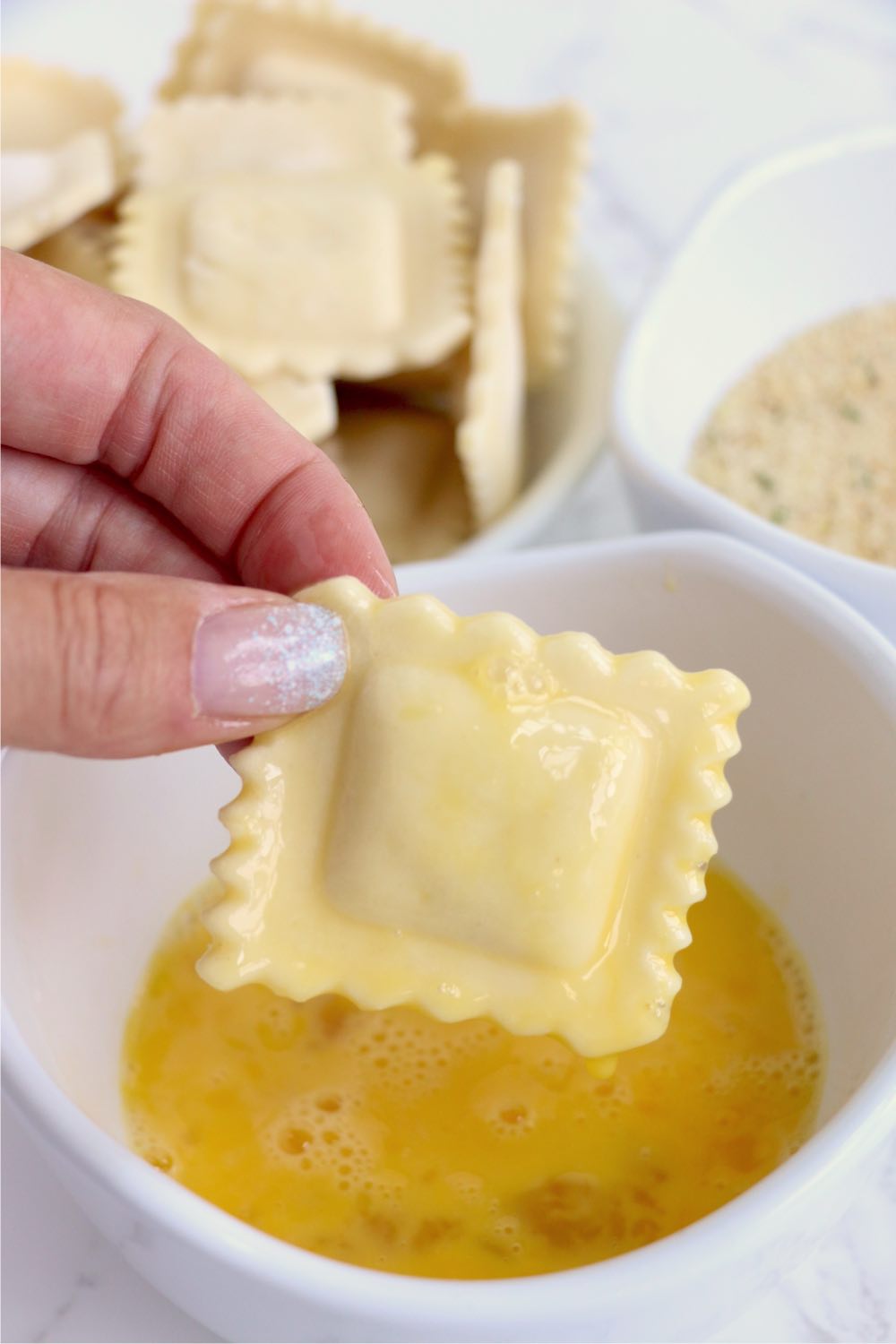 dipping cheese ravioli in egg