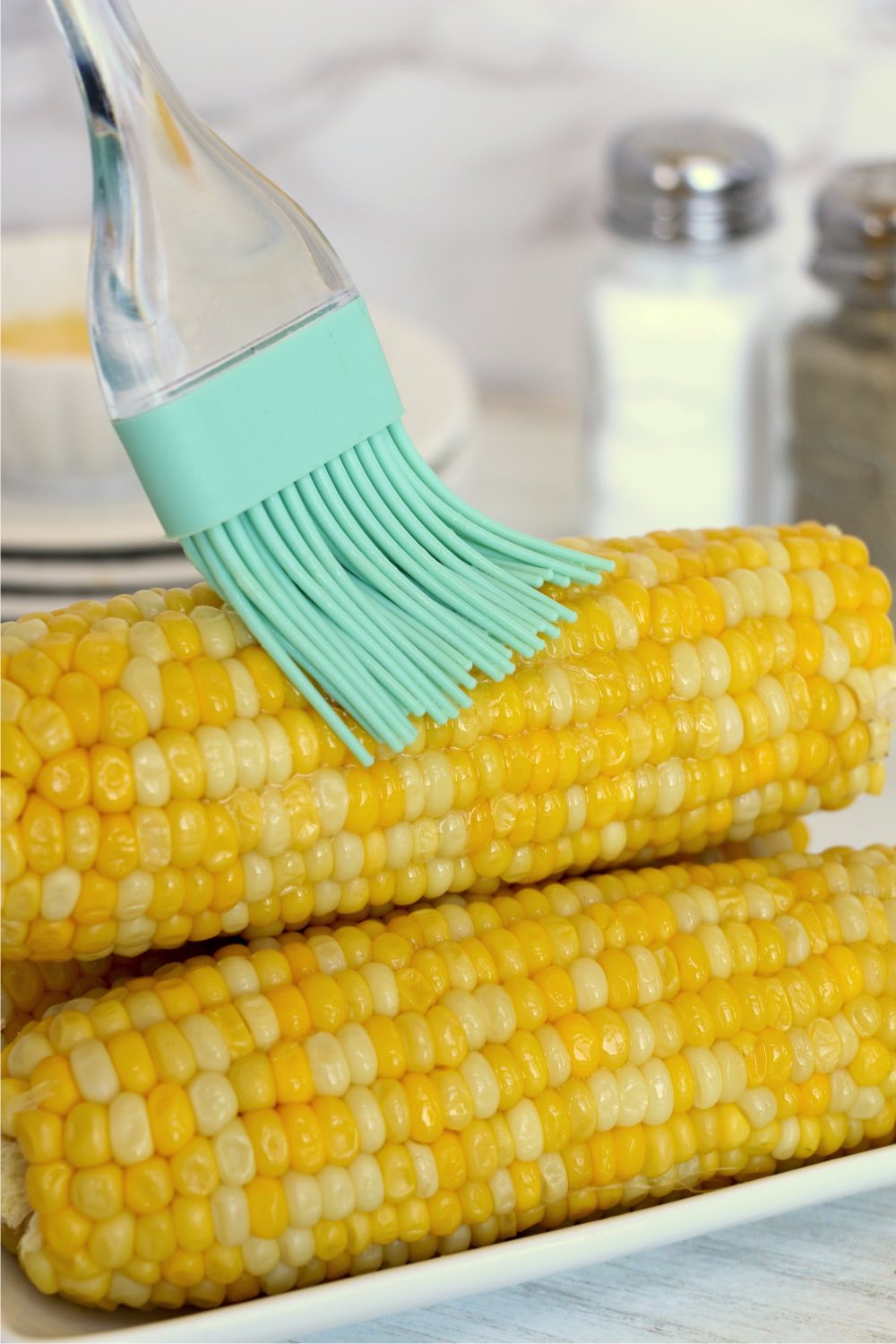 brushing butter on corn on the cob