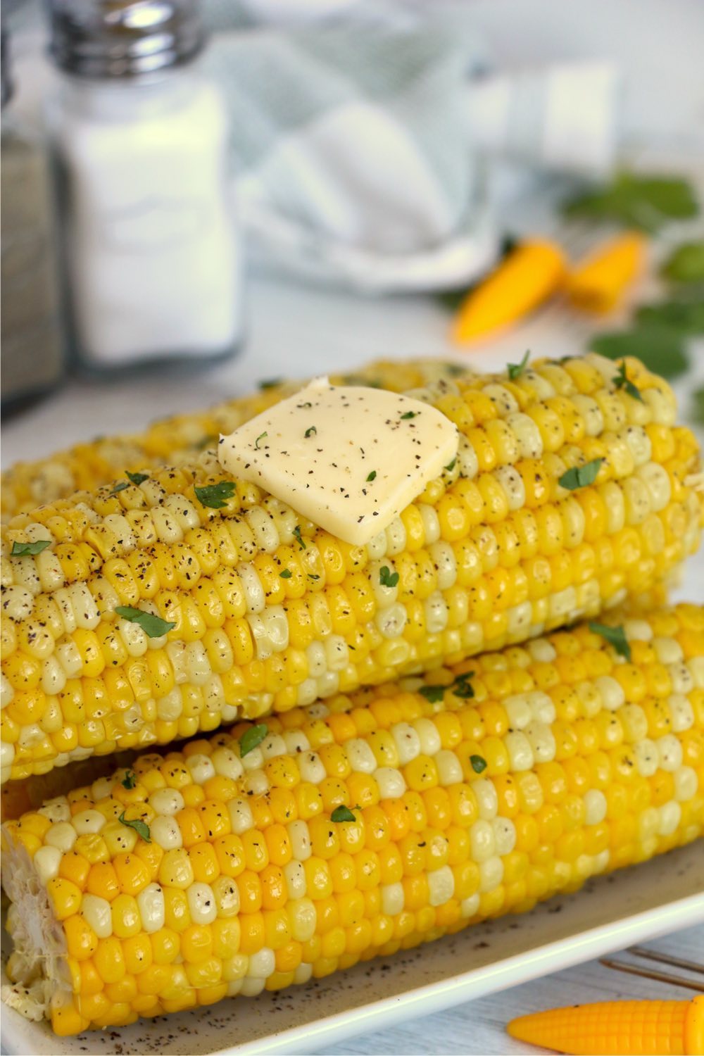 Stack of corn on the cob with butter and parsley garnish