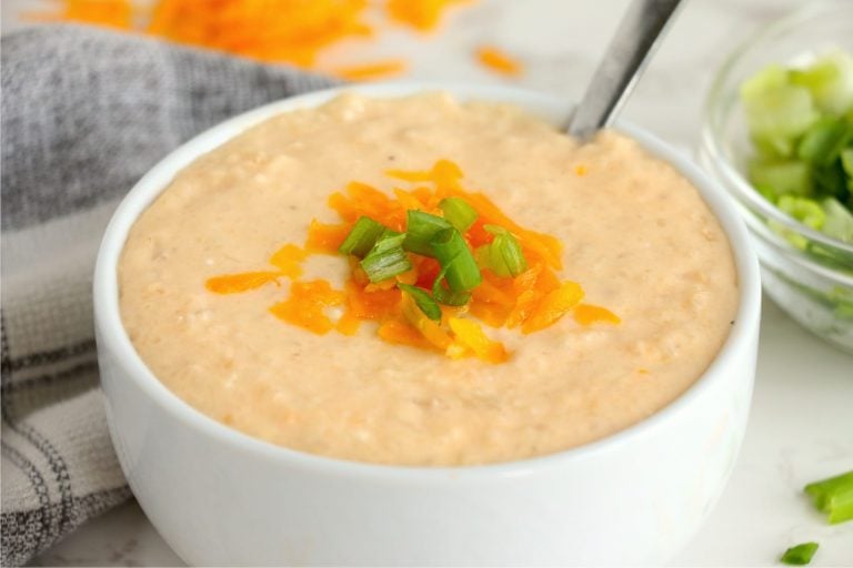 white bowl of cauliflower soup with cheese and onions