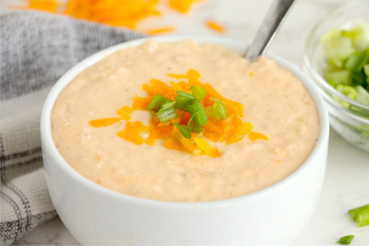 white bowl of cauliflower soup with cheese and onions