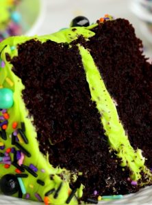 cut piece of chocolate layer cake with neon green frosting