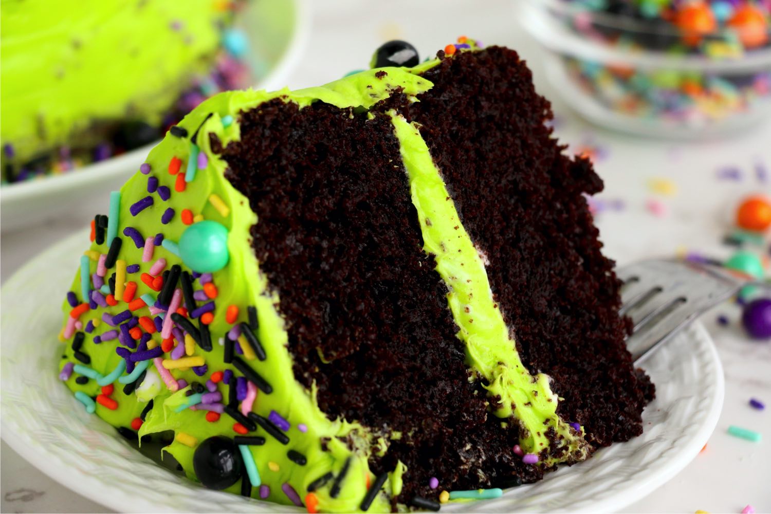 cut piece of chocolate layer cake with neon green frosting