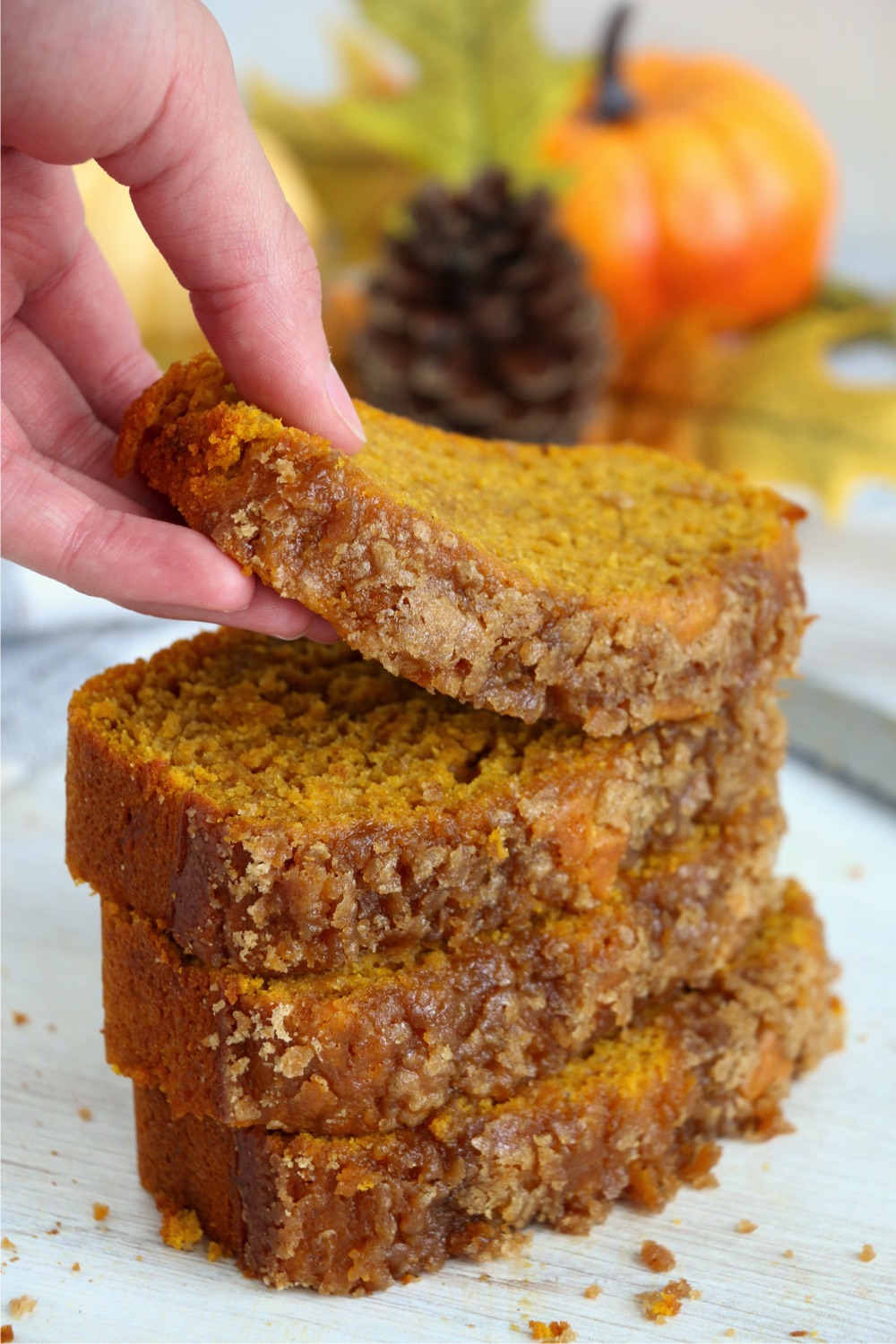 showing off a slice from a stack of pumpkin bread