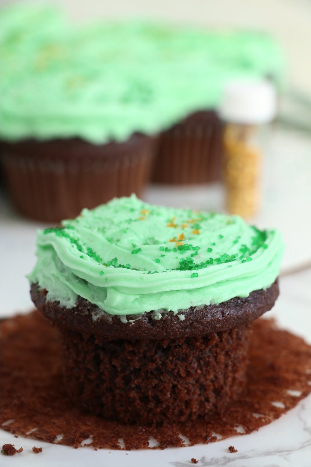 chocolate cupcake with green frosting and gold sprinkles