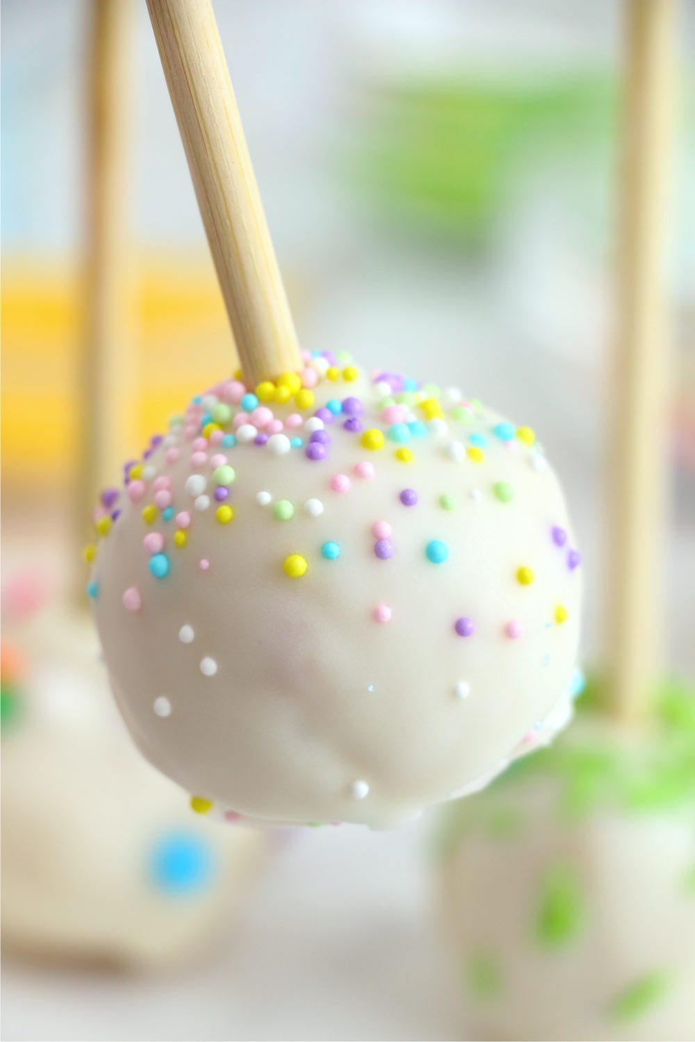 holding a cake pop decorated with nonpareils