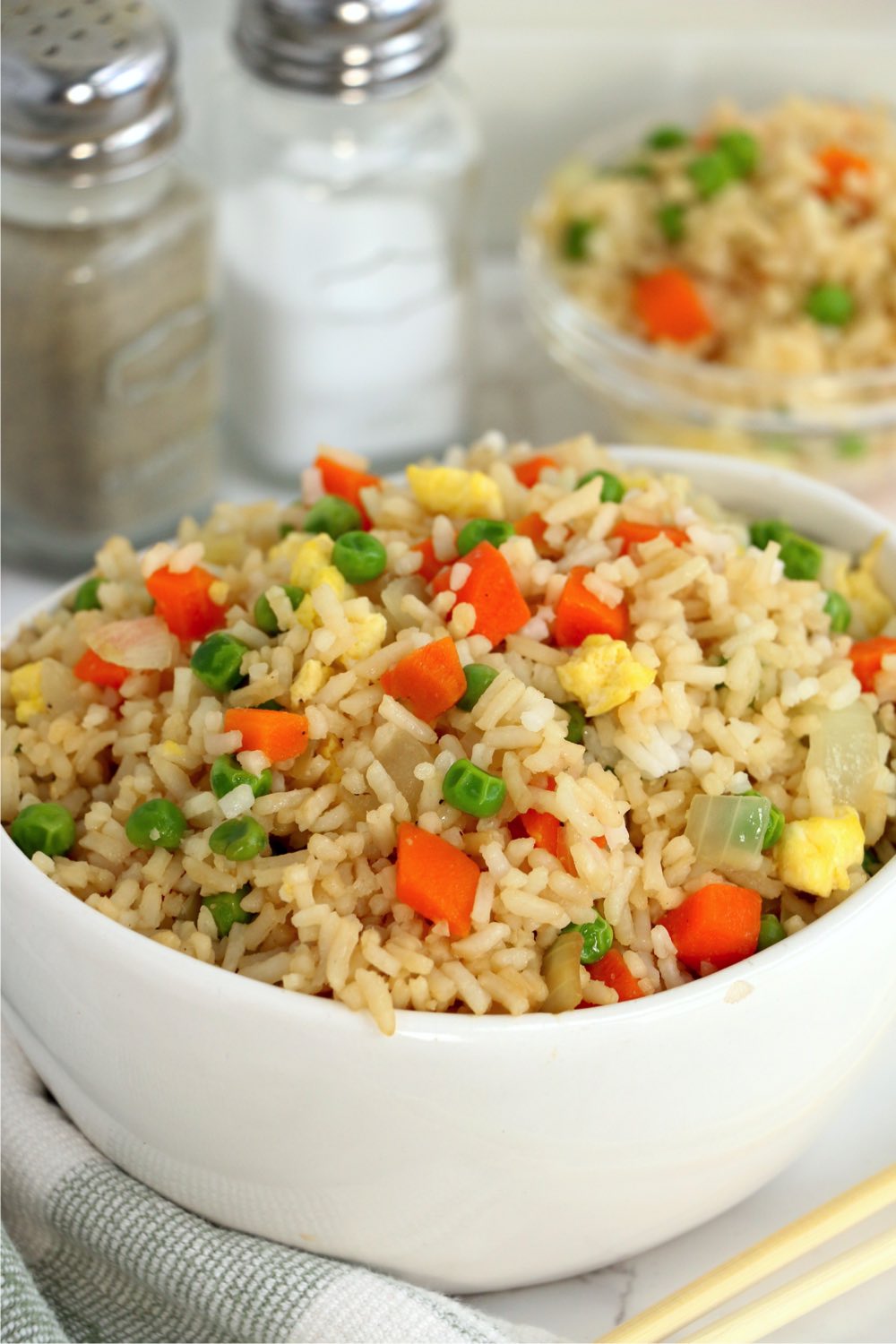 bowl of fried rice with salt and pepper in the background