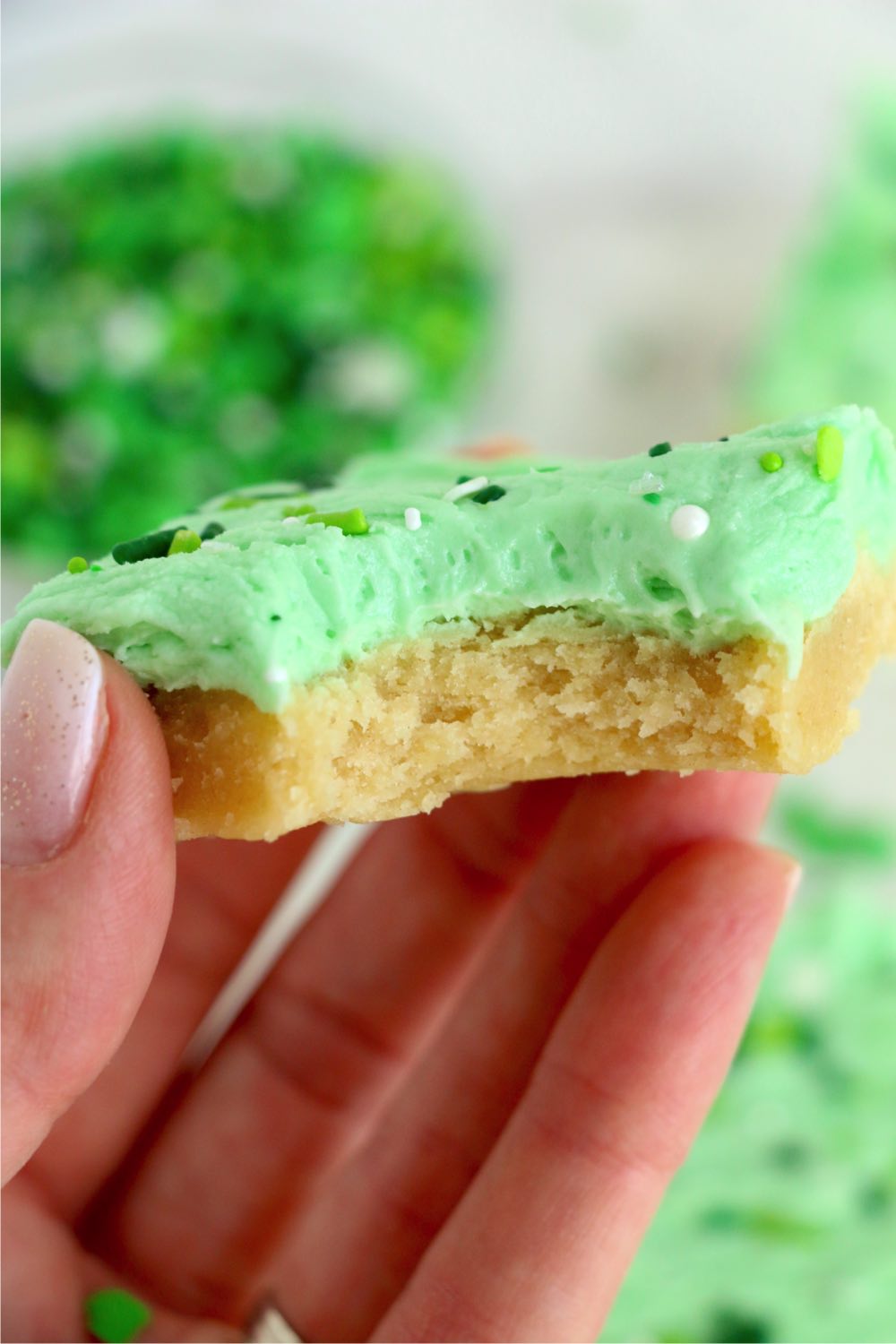 holding a sugar cookie bar with a bite out of