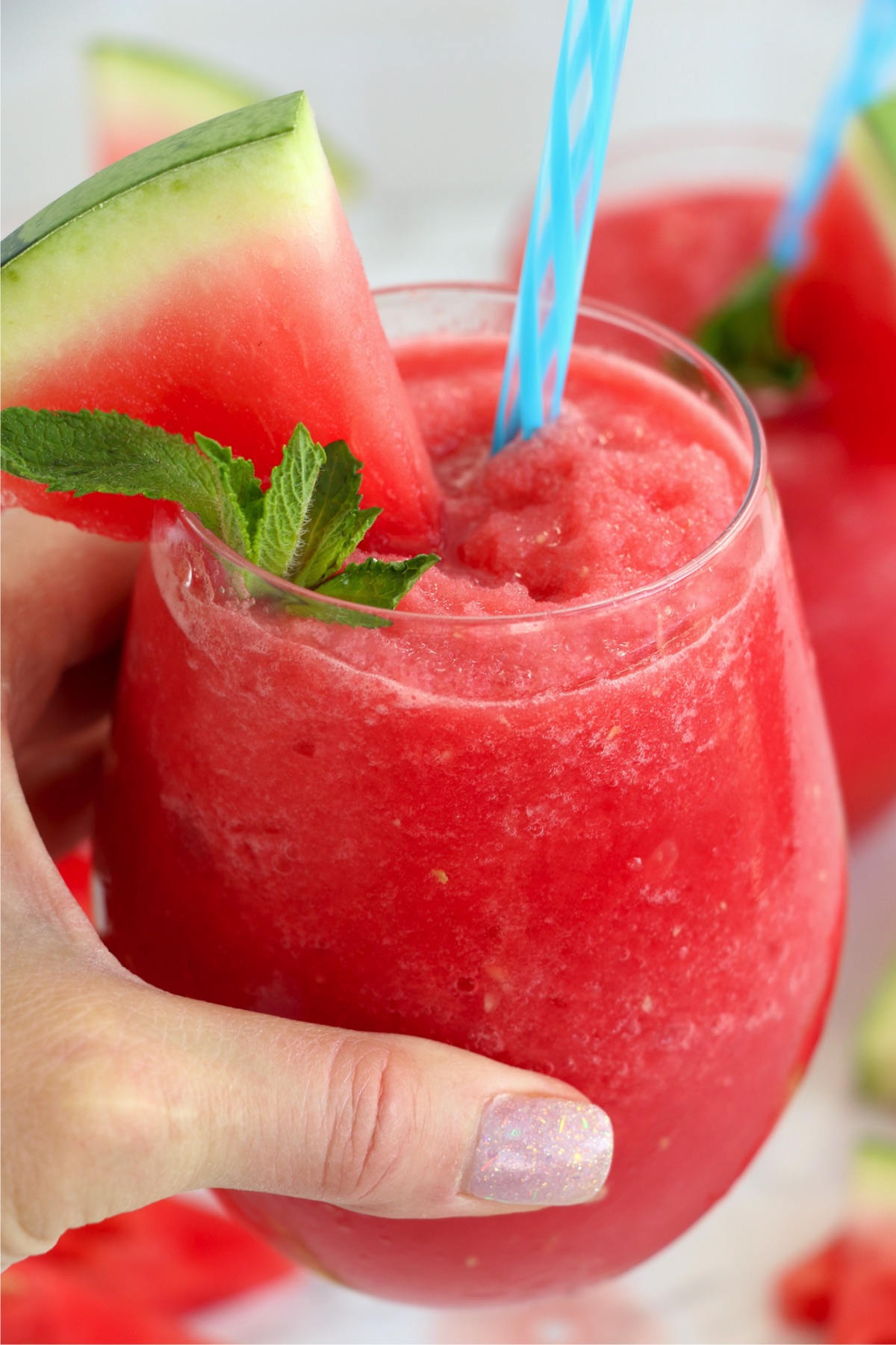 Hand holding watermelon slushy in glass