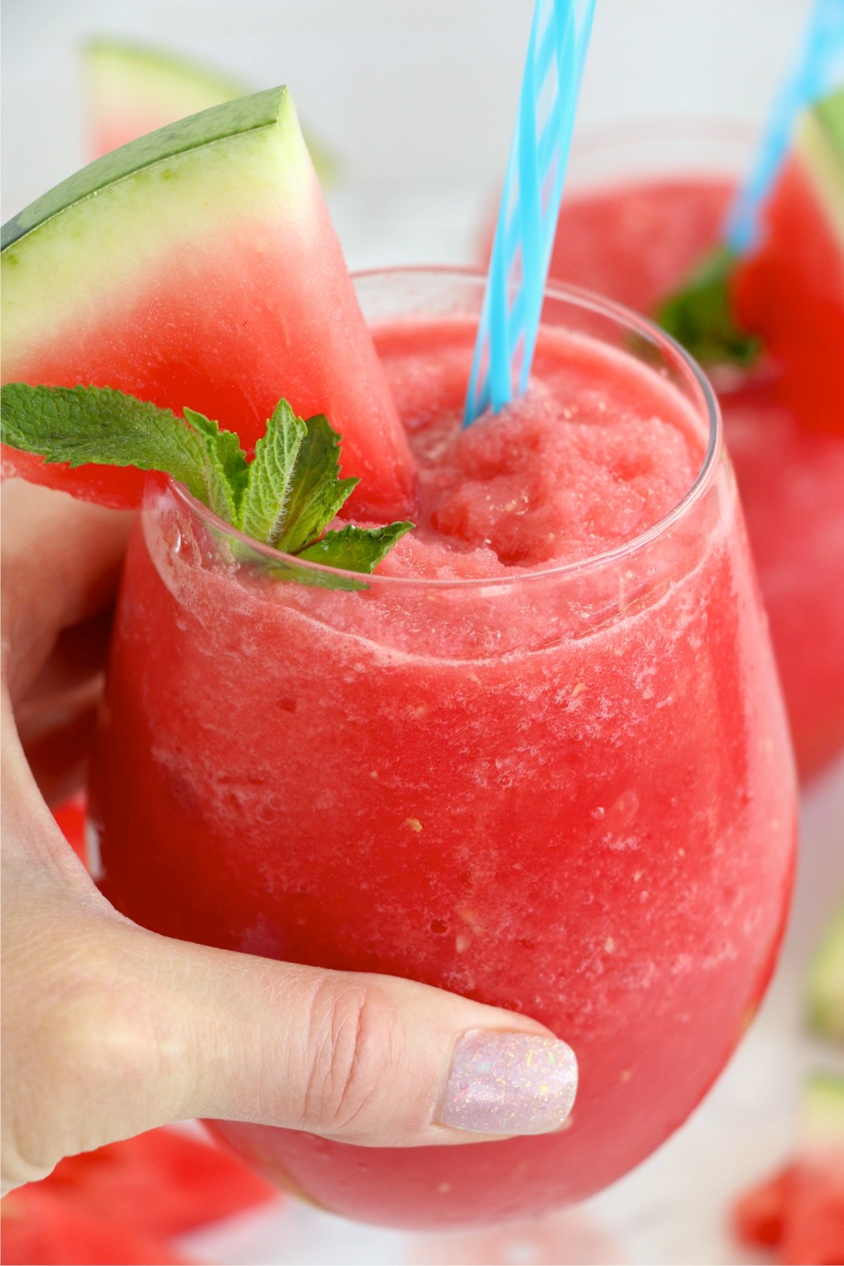 Hand holding watermelon slushy in glass