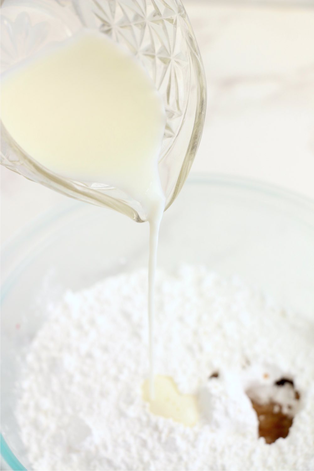 adding milk to powdered sugar and vanilla extract to make icing