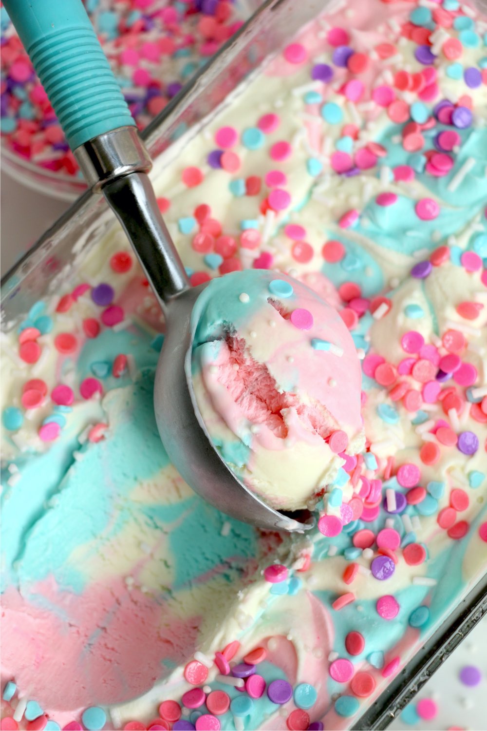 scooping pink and blue ice cream out of a pan