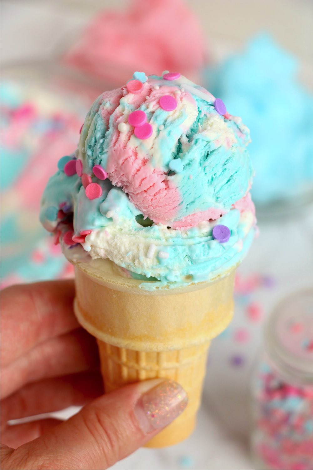holding an ice cream cone filled with cotton candy ice cream