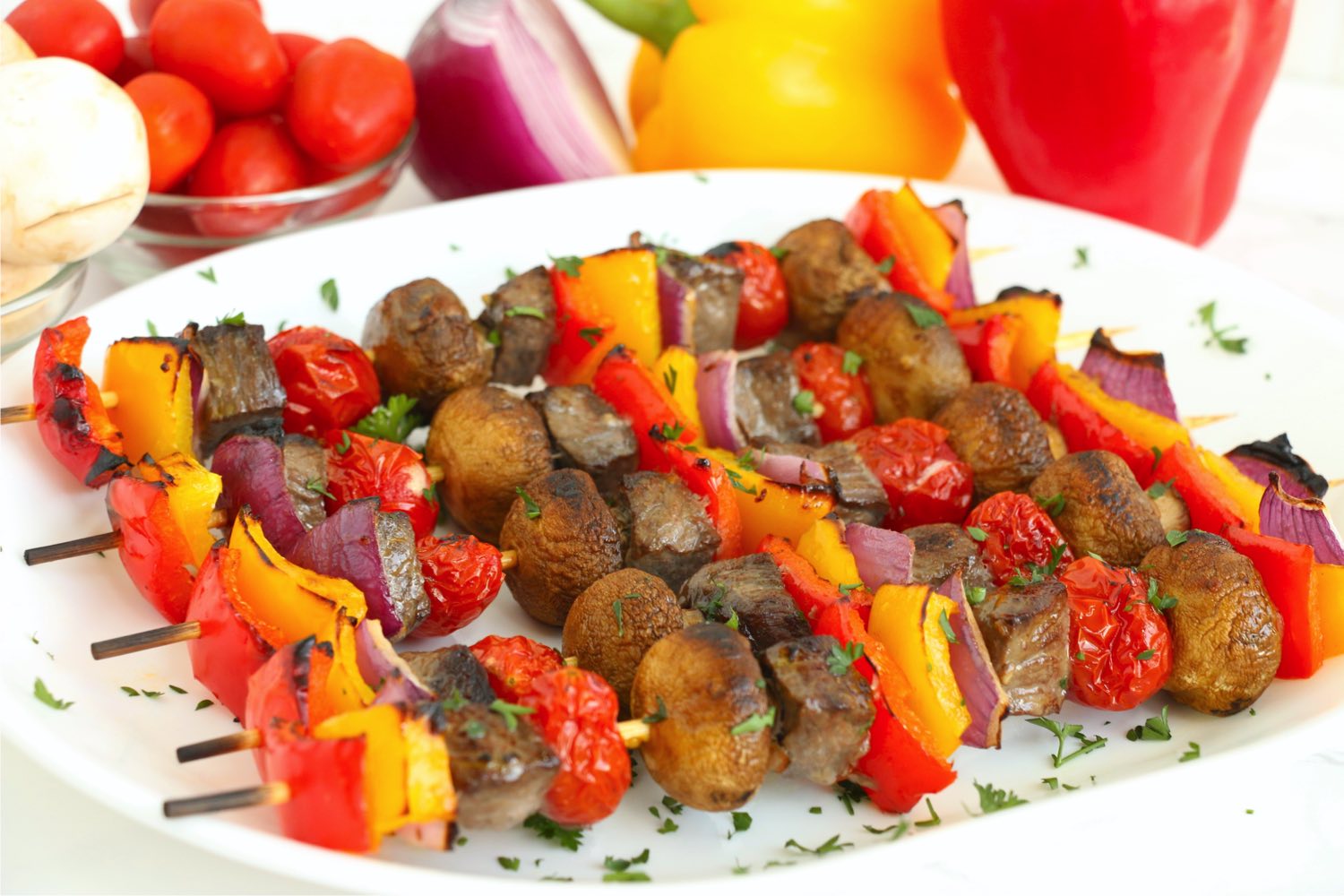 white platter filled with colorful meat and veggie kabobs