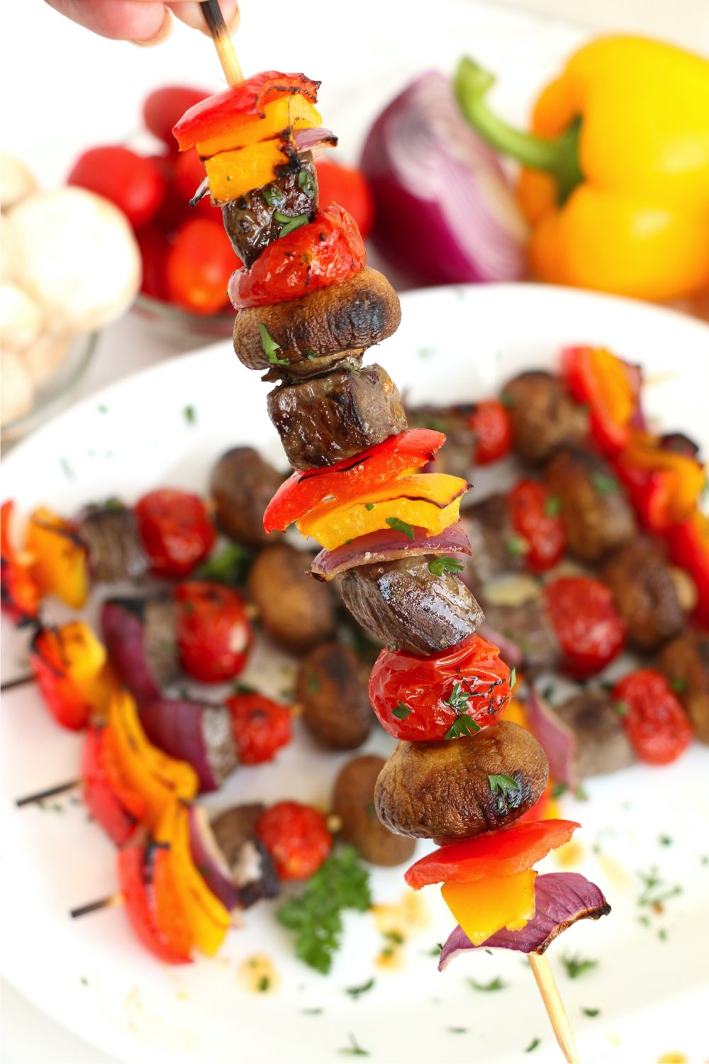 holding up a skewer filled with steak and colorful vegetables