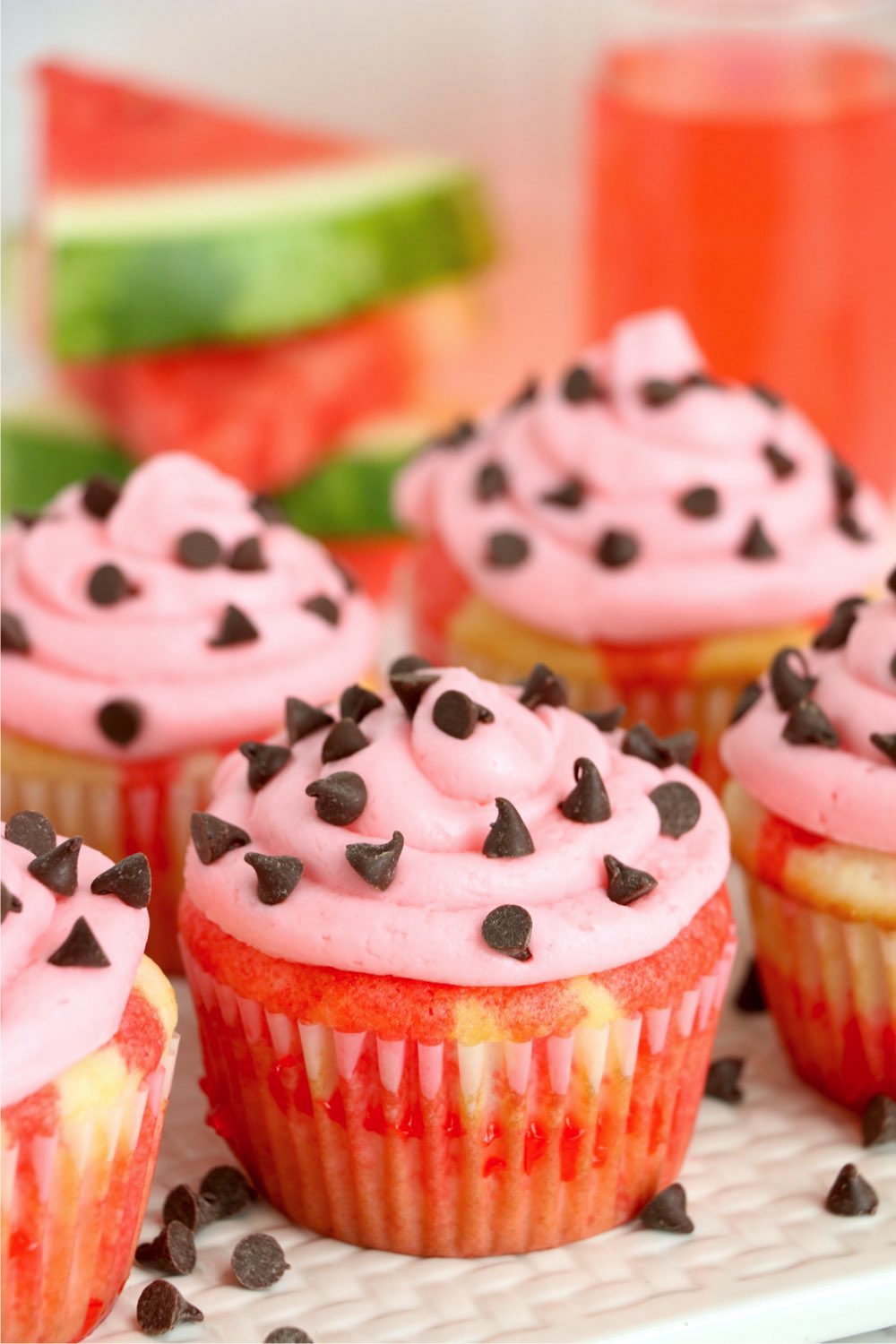 Group of watermelon cupcakes with watermelon and kool-aid in background