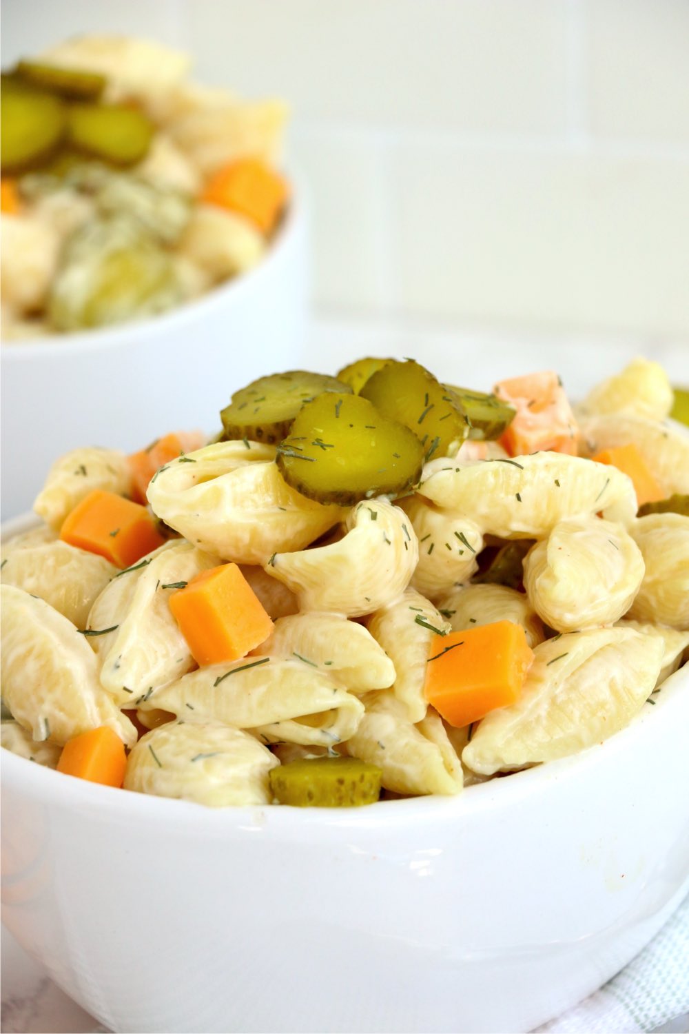 bowl of pasta salad with cubes of cheese and pickles