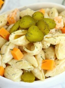 bowl of pasta salad with sliced pickles on top