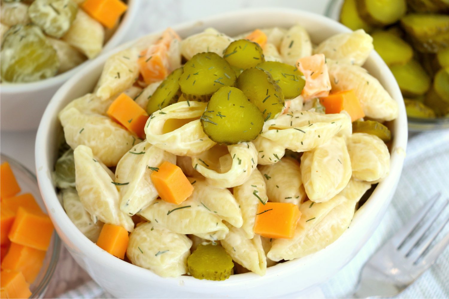 bowl of pasta salad with sliced pickles on top