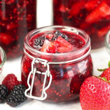 open jar of jam surrounded by fresh berries