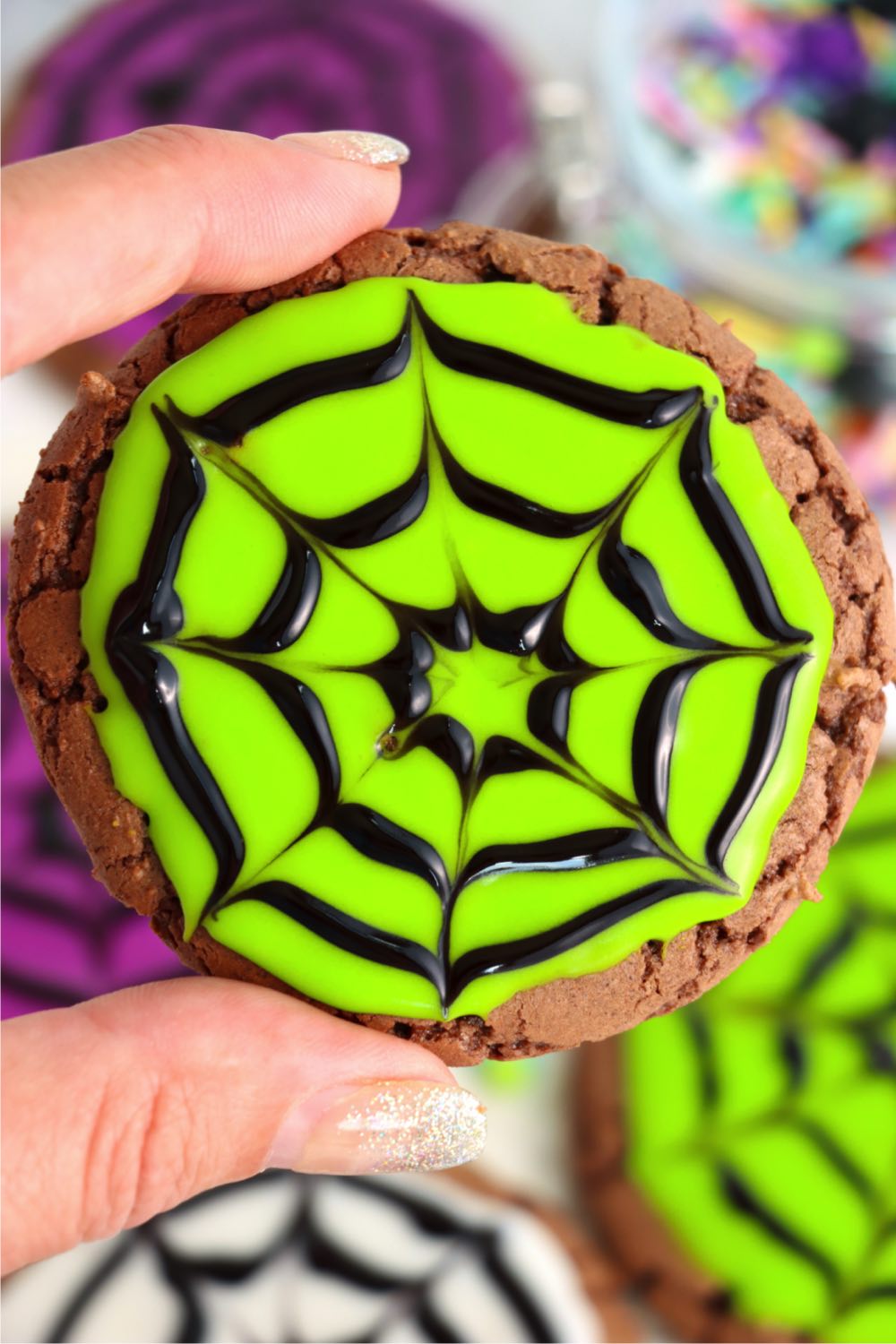 holding up a neon green spider web cookie