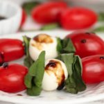 caprese skewers with balsamic glaze on a white plate