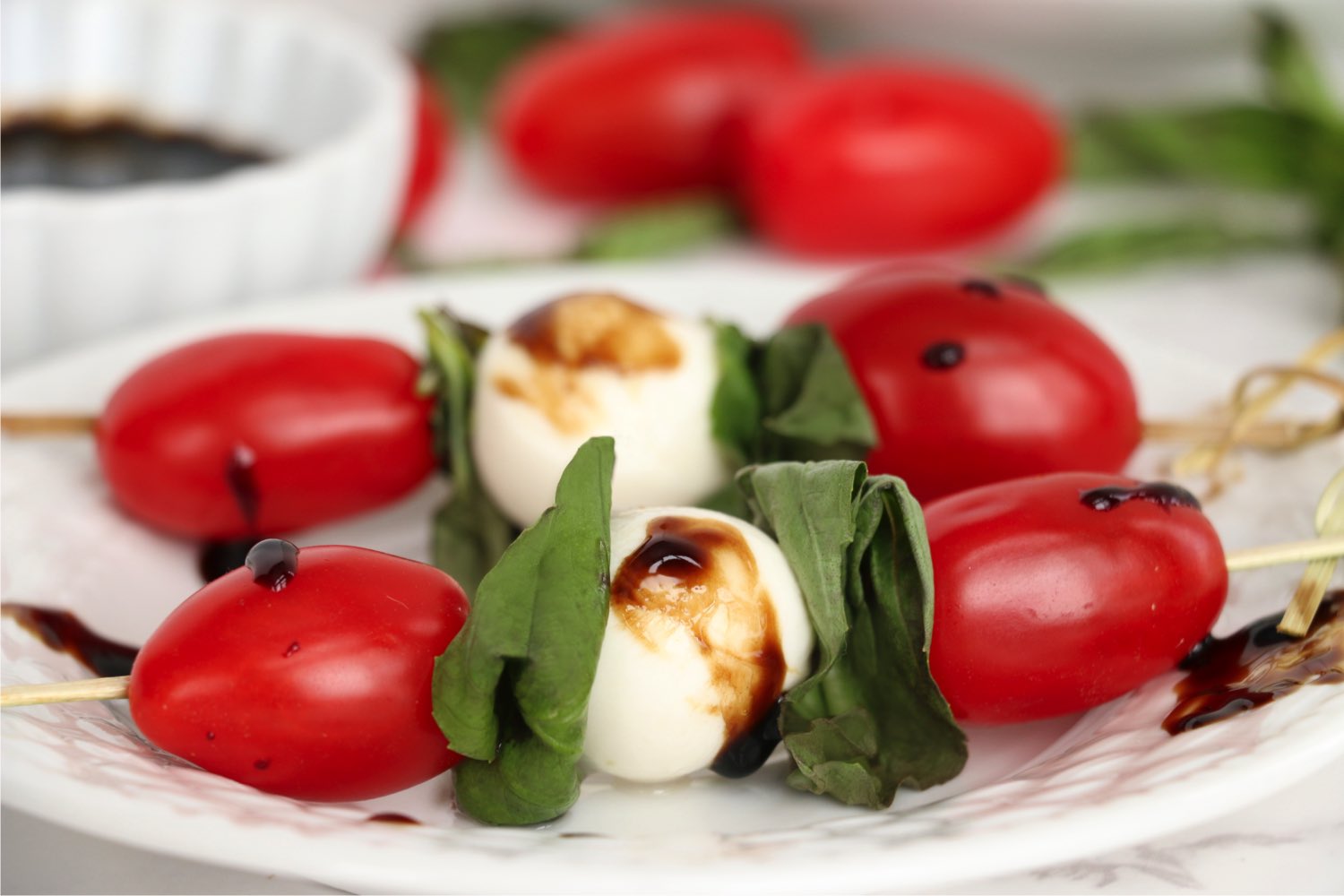 caprese skewers with balsamic glaze on a white plate