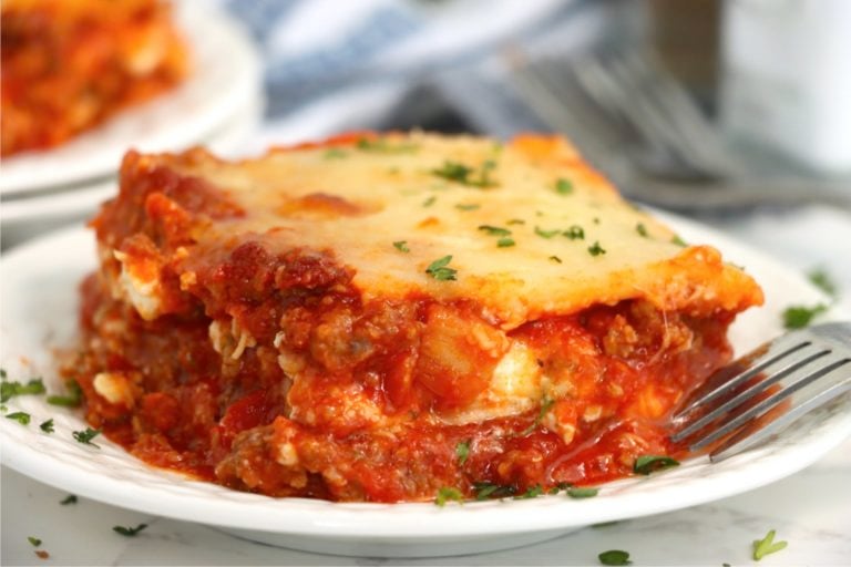 close up shot of a large piece of lasagna on a plate