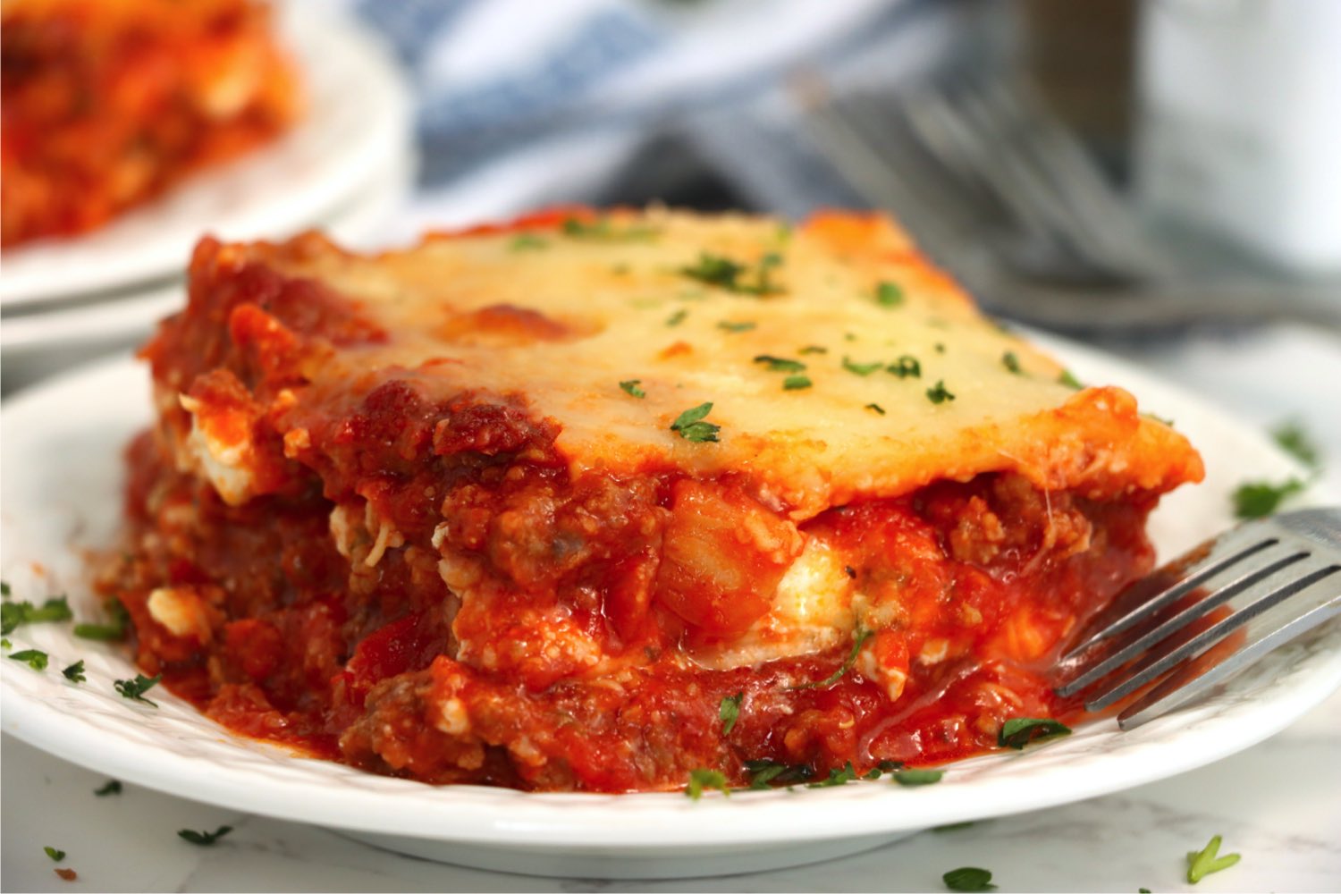 close up shot of a large piece of lasagna on a plate