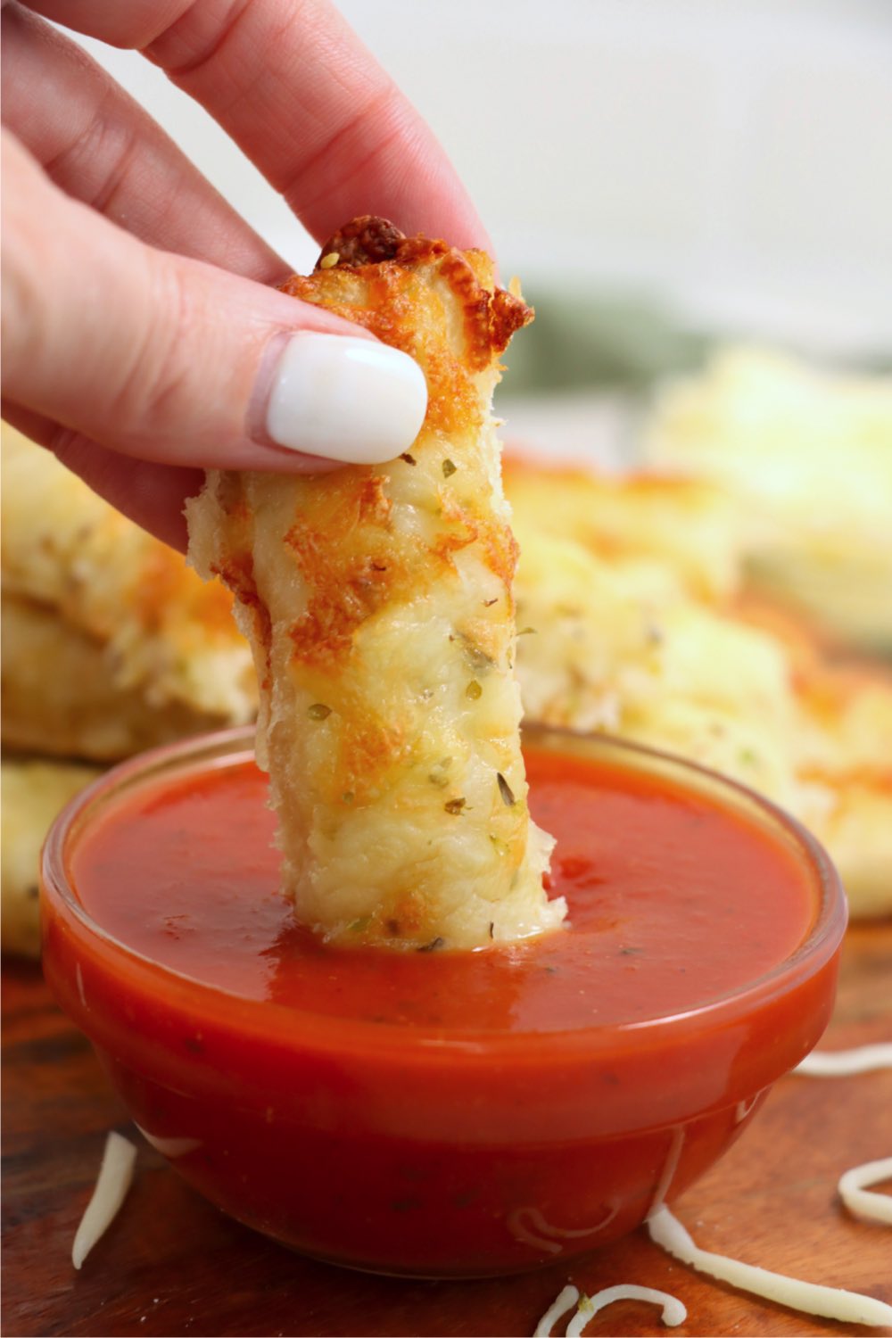 dunking a cheesy breadstick into a bowl of marinara sauce