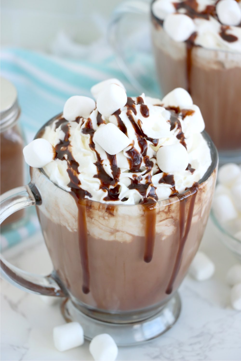 glass mug of hot chocolate with marshmallows and chocolate syrup