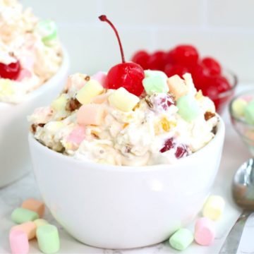 white bowl filled with fruit salad topped with a cherry