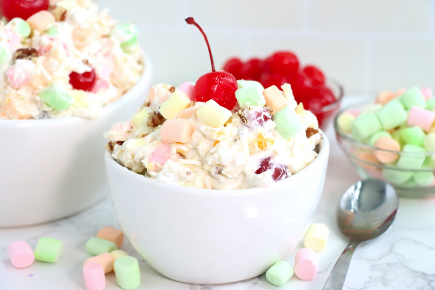 white bowl filled with fruit salad topped with a cherry