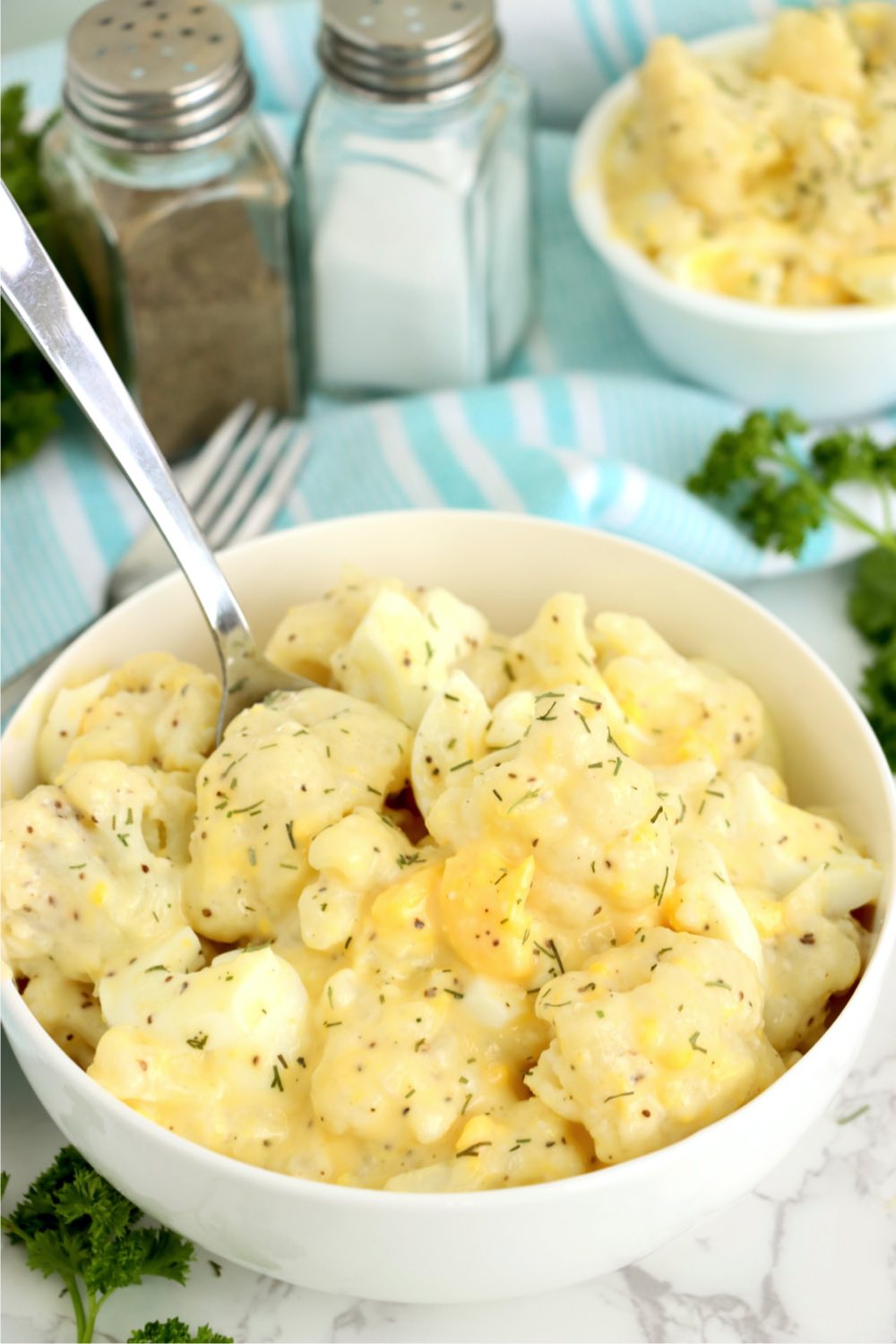 bowl of cauliflower potato salad with spoon in it