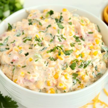 bowl of corn dip surrounded by chips and fresh ingredients