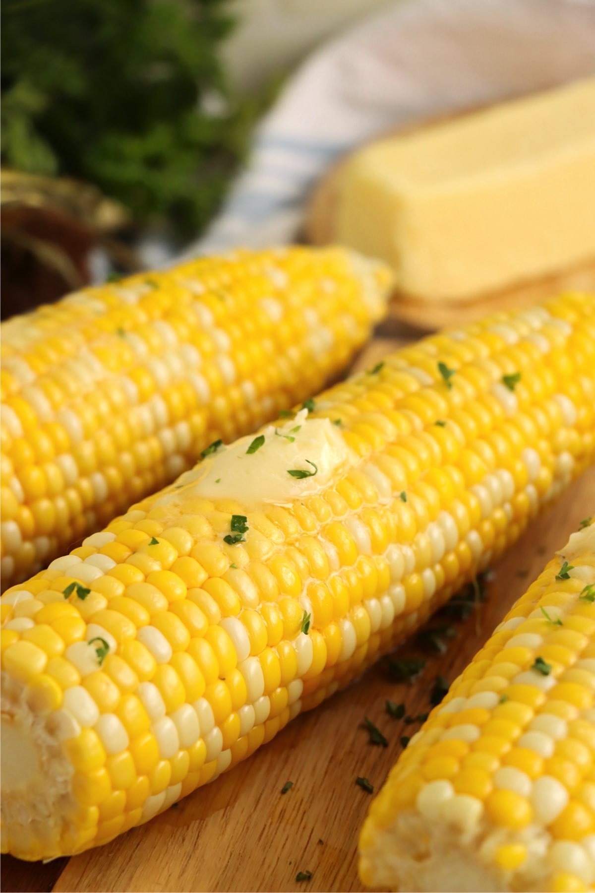 close up of cobs of corn with butter pats on them