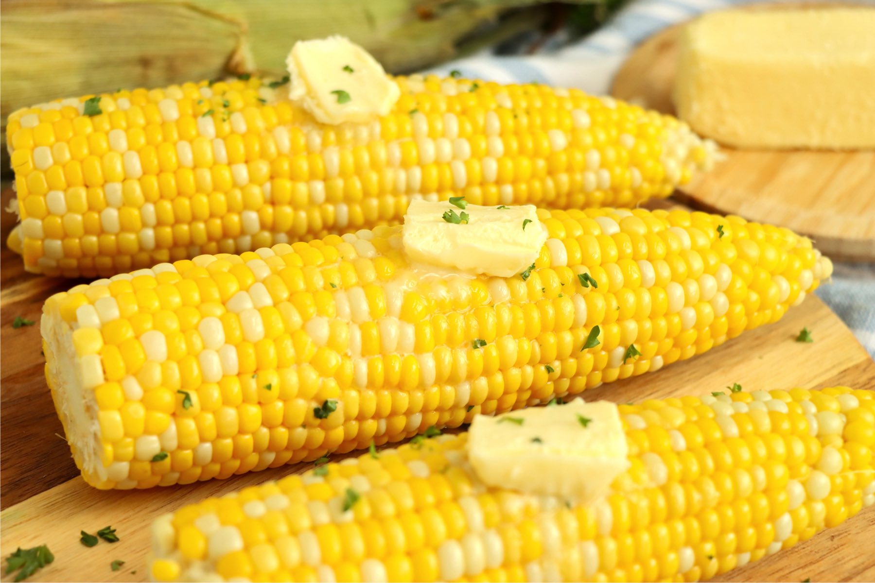 butter pats on cooked cobs of corn