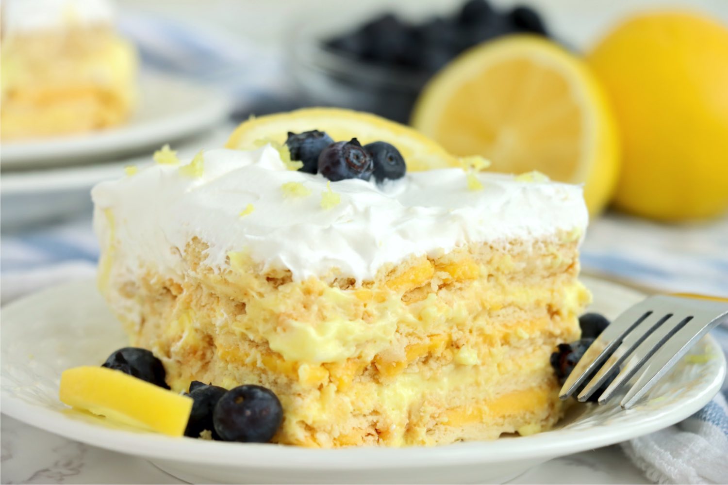up close shot of layered lemon cake garnished with lemon wedge and blueberries