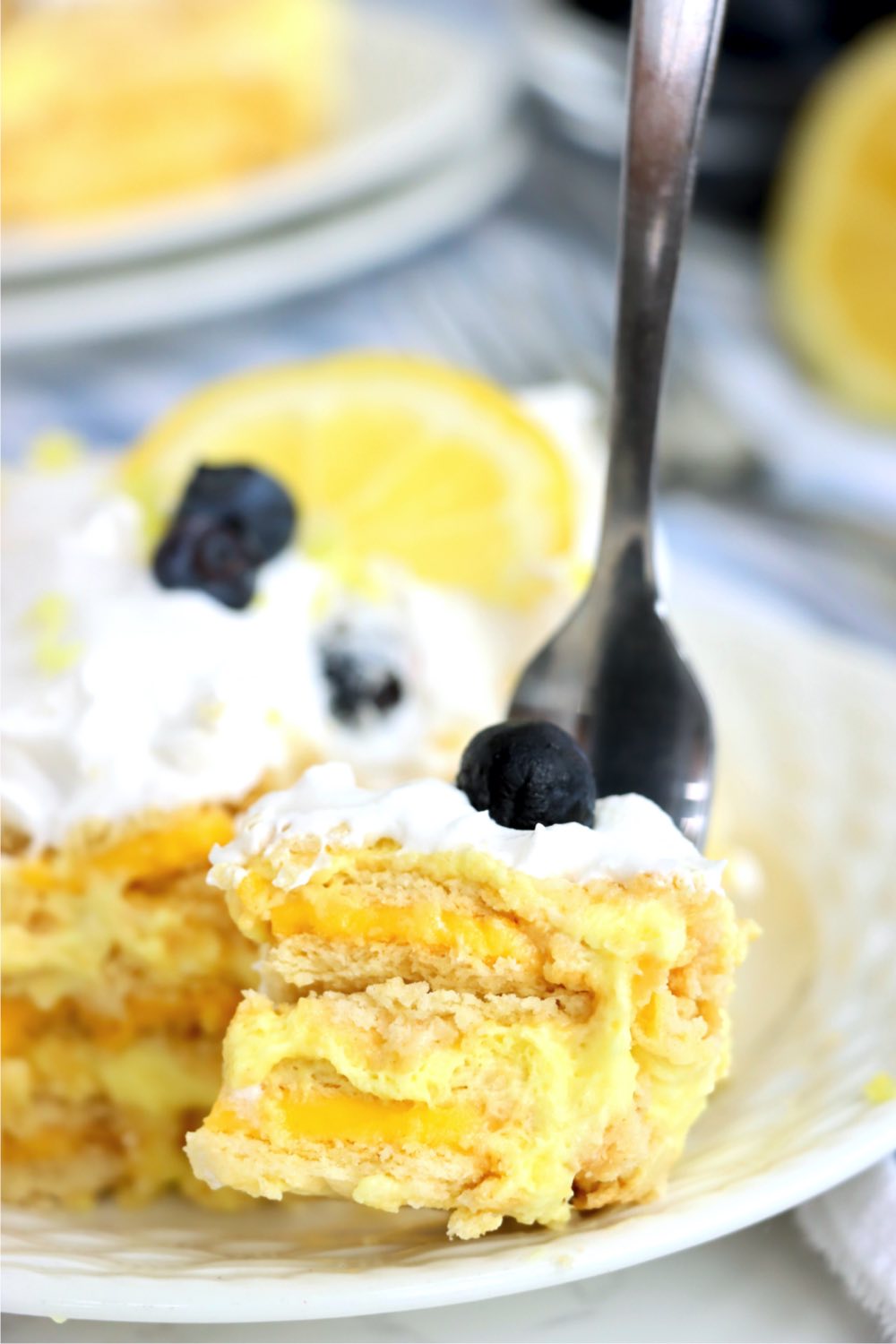 fork digging into lemon layered cake with blueberries