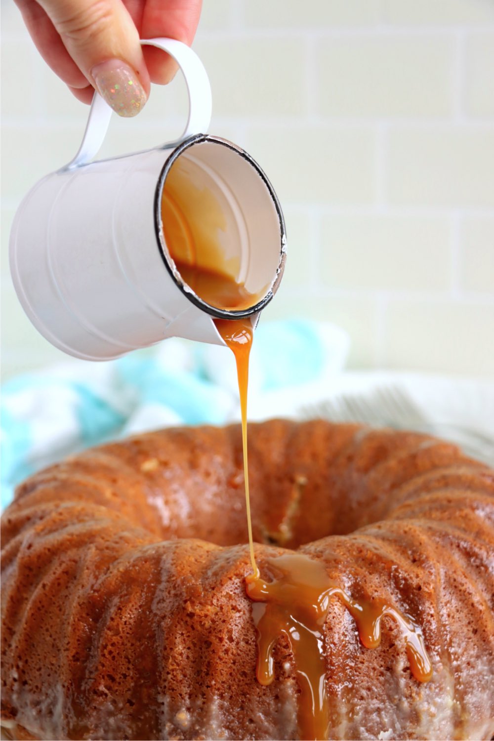 pouring caramel sauce over the top of a bundt cake