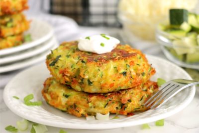 small stack of zucchini patties on a white plate