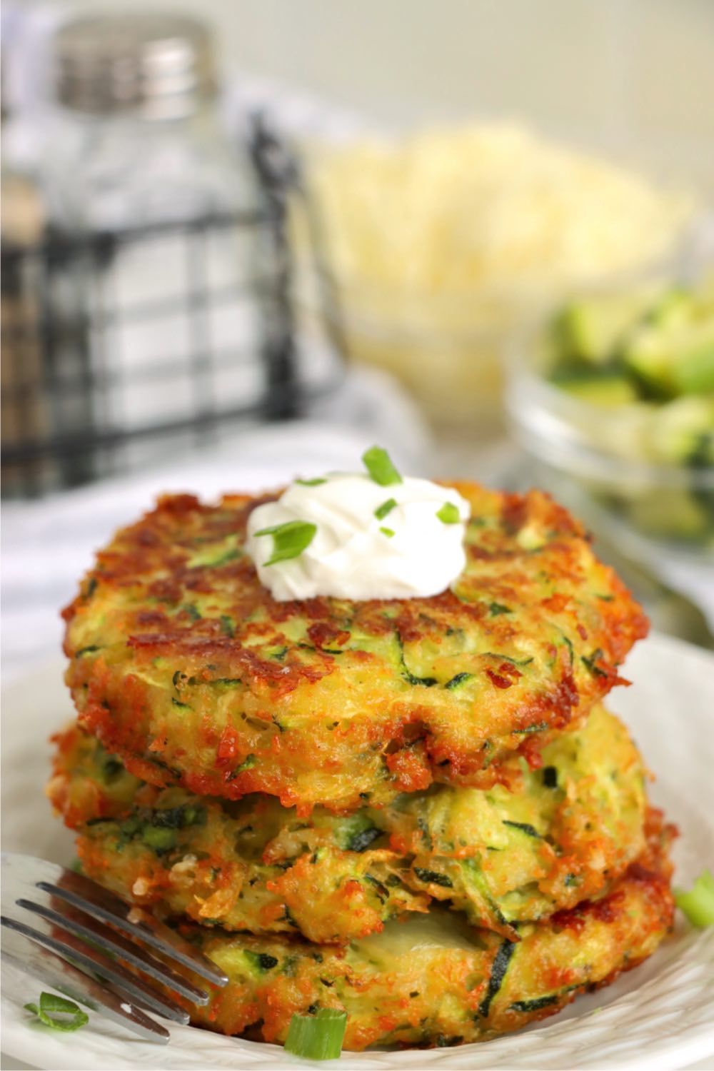 stack of fried zucchini patties with sour cream dollop on top