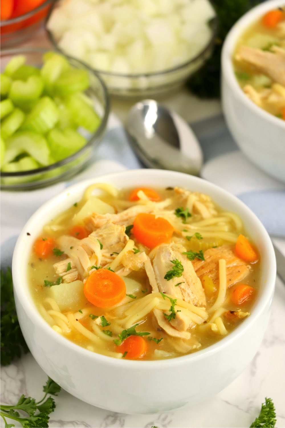 white bowl of turkey and noodle soup with spoon nearby