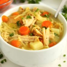 A bowl of soup filled with carrots, potatoes and turkey