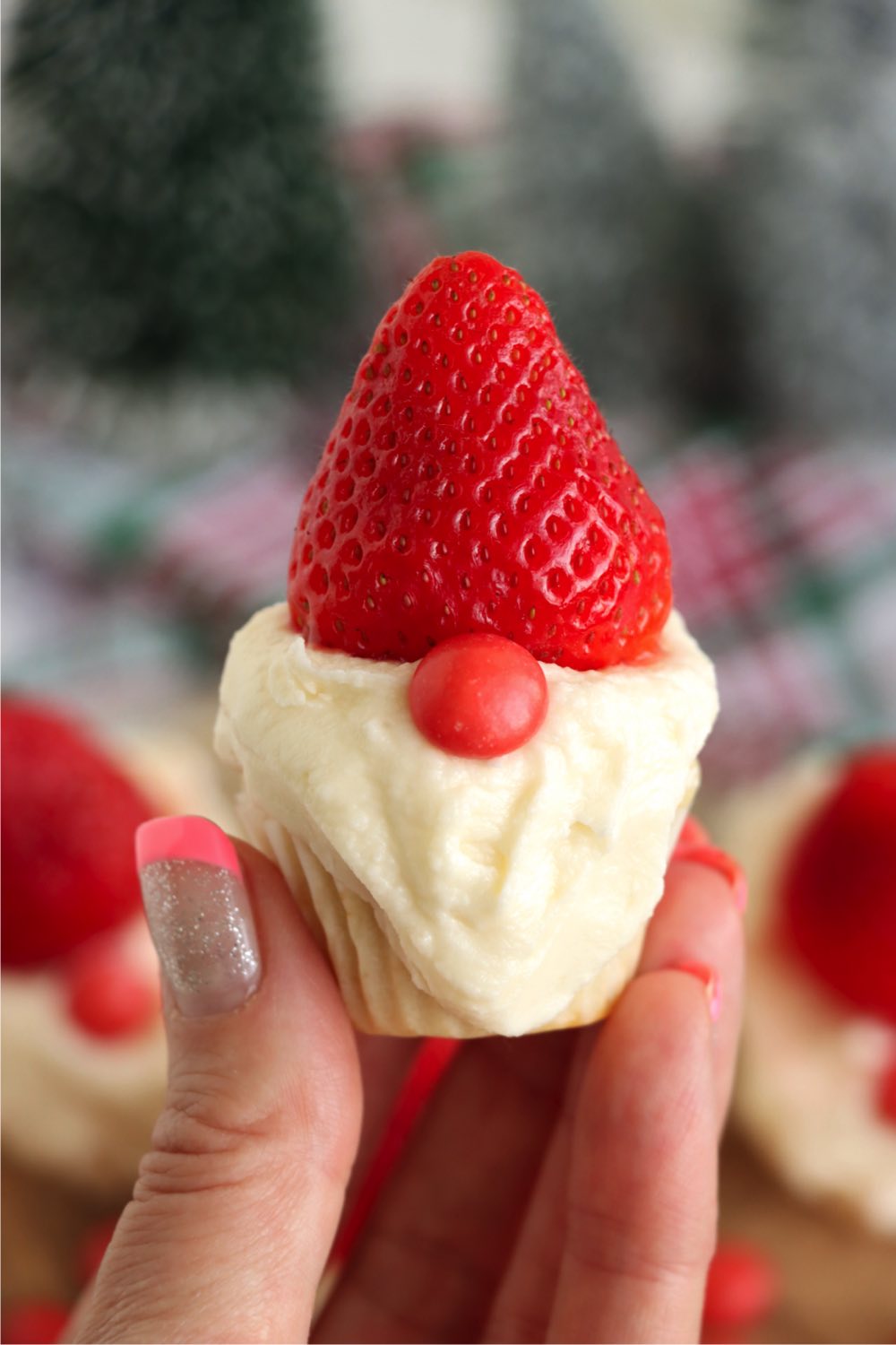 hand holding up a gnome cupcake with a strawberry hat