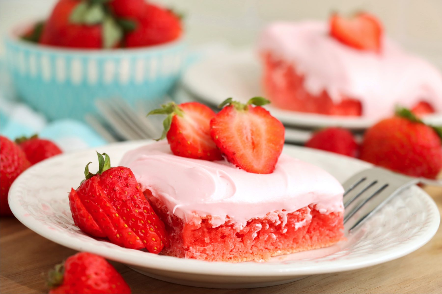 white dessert plate holding a strawberry brownie topped with fresh strawberries
