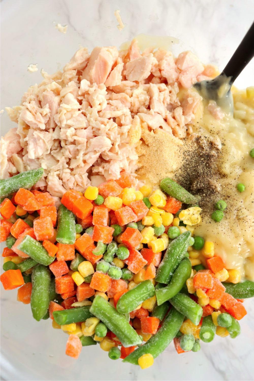 Chicken, mixed vegetables and seasonings in a bowl