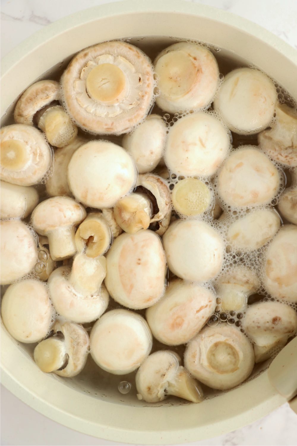 Pot of water filled with fresh button mushrooms