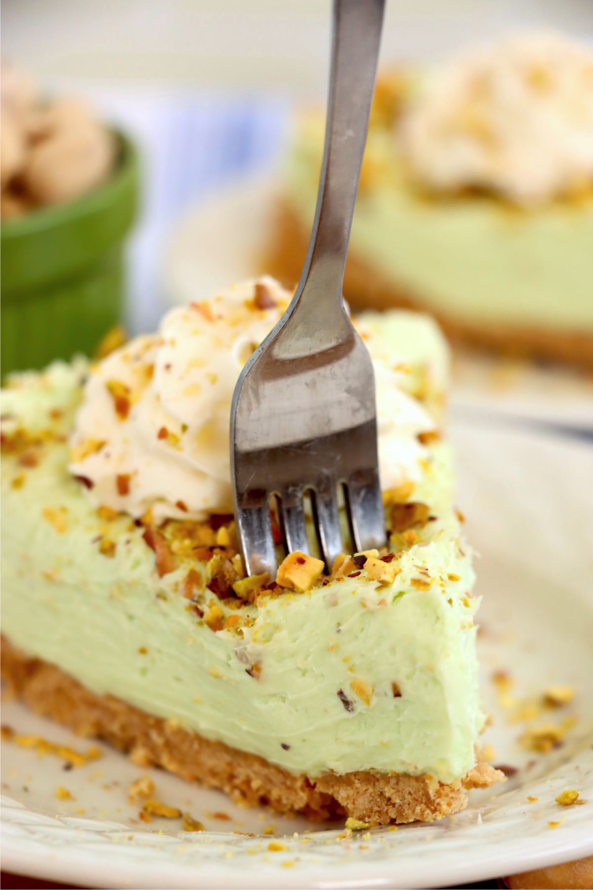 Fork digging into a piece of pistachio cheesecake